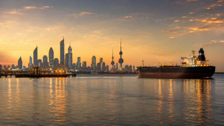 Kuwait City skyline at sunset with an oil tanker on the Gulf, illustrating Kuwait sovereign credit ratings during the Strait of Hormuz shock