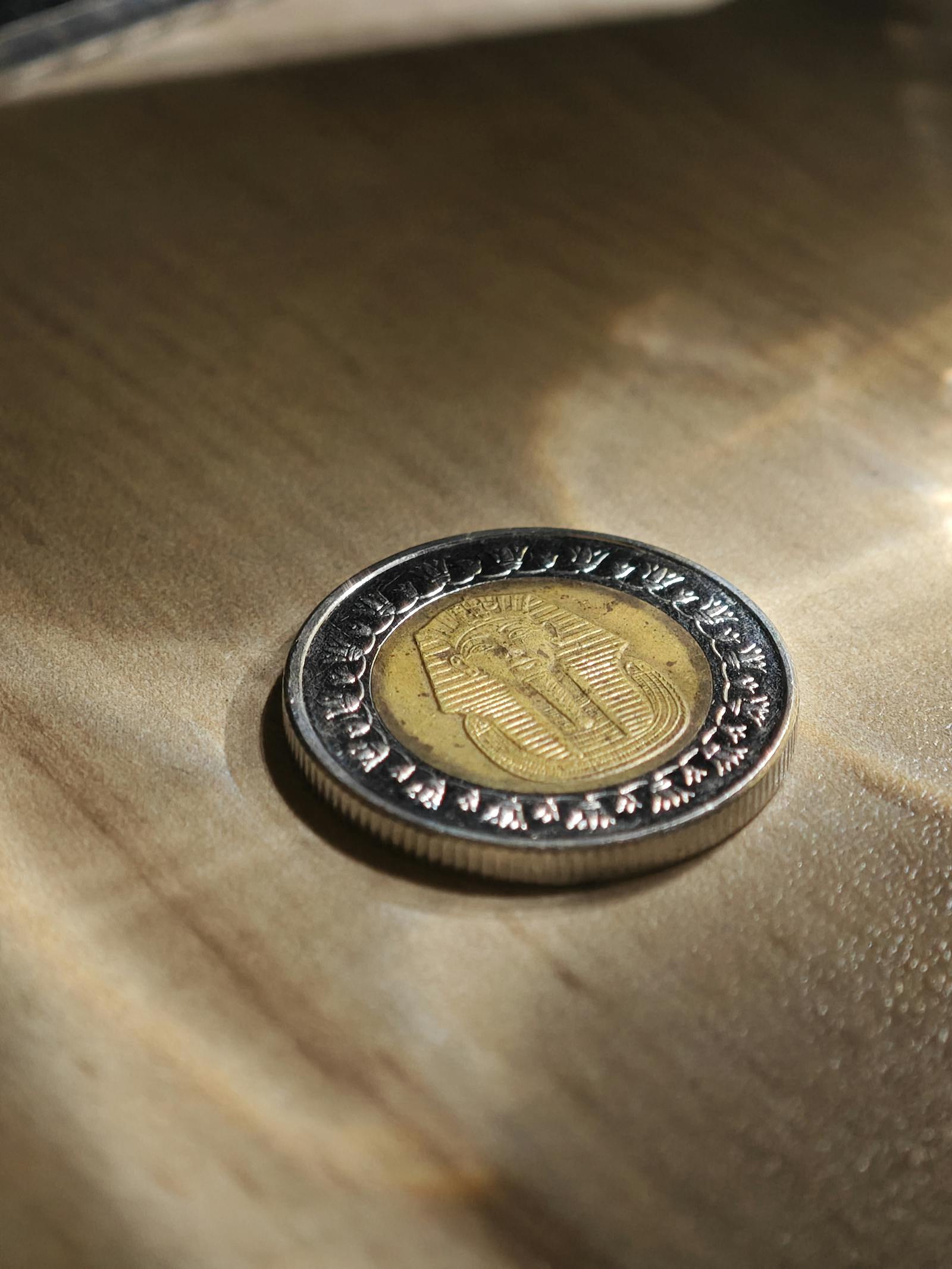 An Egyptian one pound coin placed on a wooden table surface