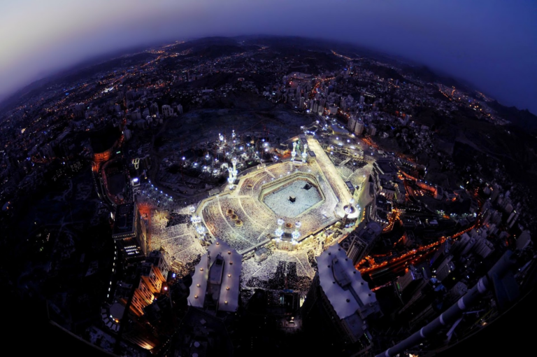 Aerial night view of the Grand Mosque and the Kaaba in Makkah, surrounded by the lit city