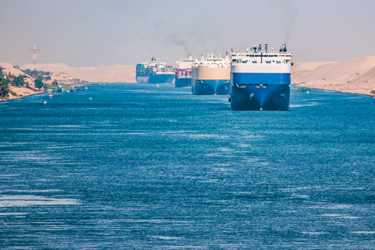 Ships Transiting the Suez Canal in Convoy, Egypt: vehicle carriers and a container ship moving in line through the canal