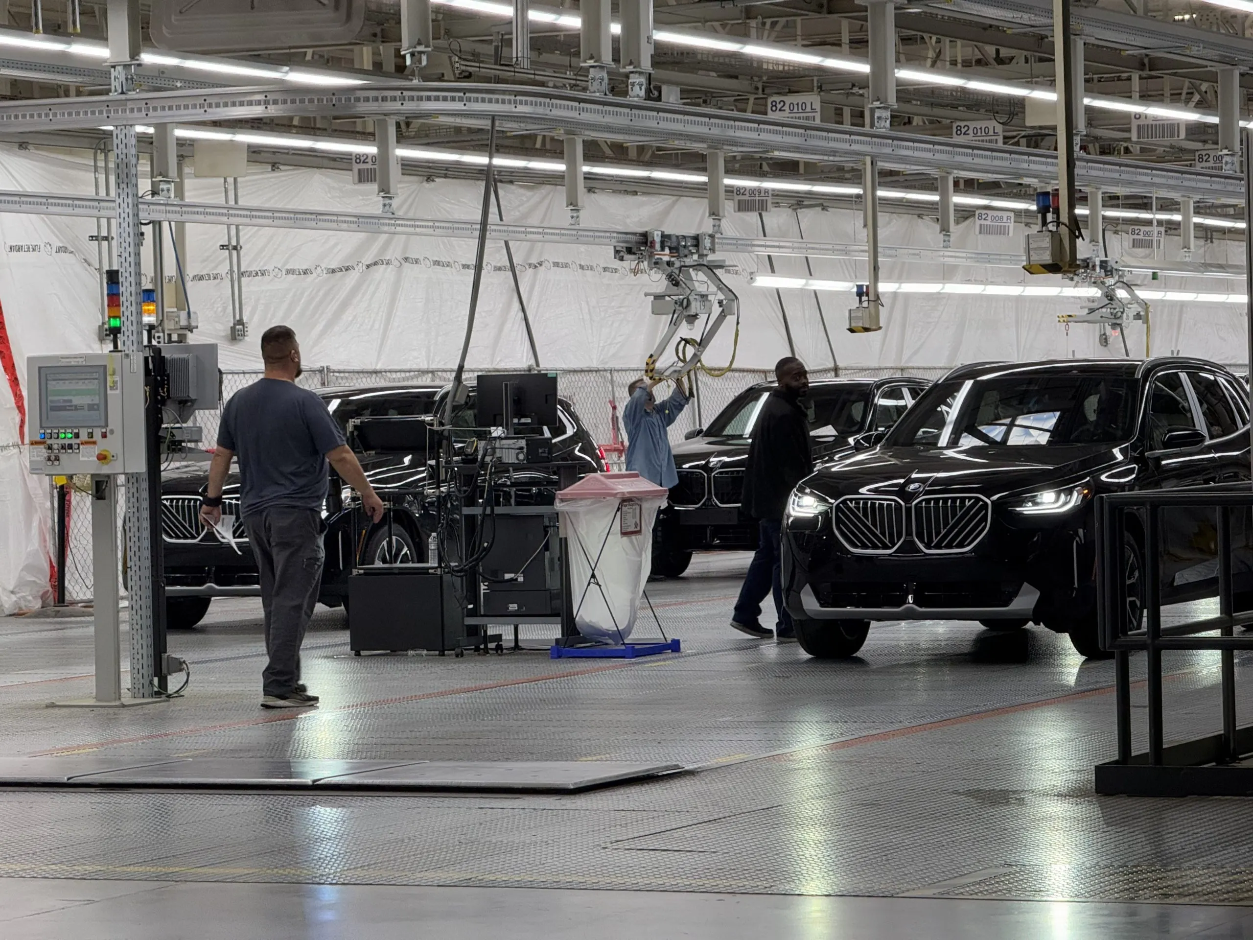 Workers beside black BMW SUVs on a vehicle assembly line in Egypt, under factory lights