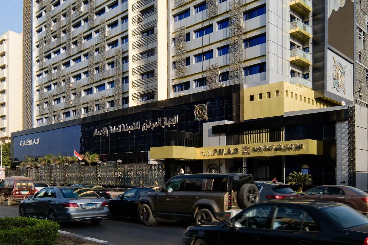 The building of Egypt's Central Agency for Public Mobilization and Statistics, with its name in Arabic, the CAPMAS lettering and emblem on the facade, an Egyptian flag and traffic in front
