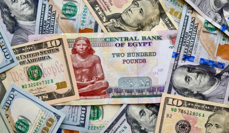 An Egyptian 200-pound banknote issued by the Central Bank of Egypt, showing the Seated Scribe statue, laid over a spread of US 100-dollar and 10-dollar bills