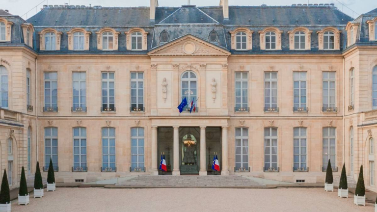 The courtyard facade of the Élysée Palace in Paris, with French and EU flags at the entrance