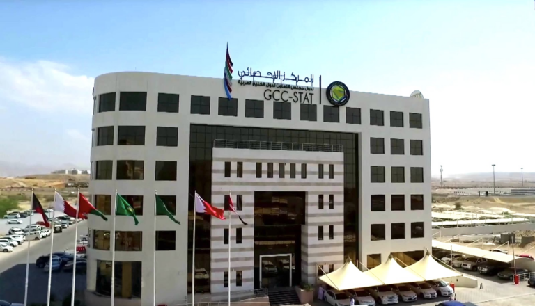The GCC Statistical Center headquarters building with its bilingual GCC-STAT sign and a row of flags in front