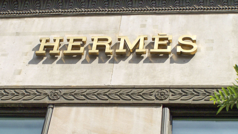 Gold HERMÈS letters mounted on a carved stone shopfront facade above two windows