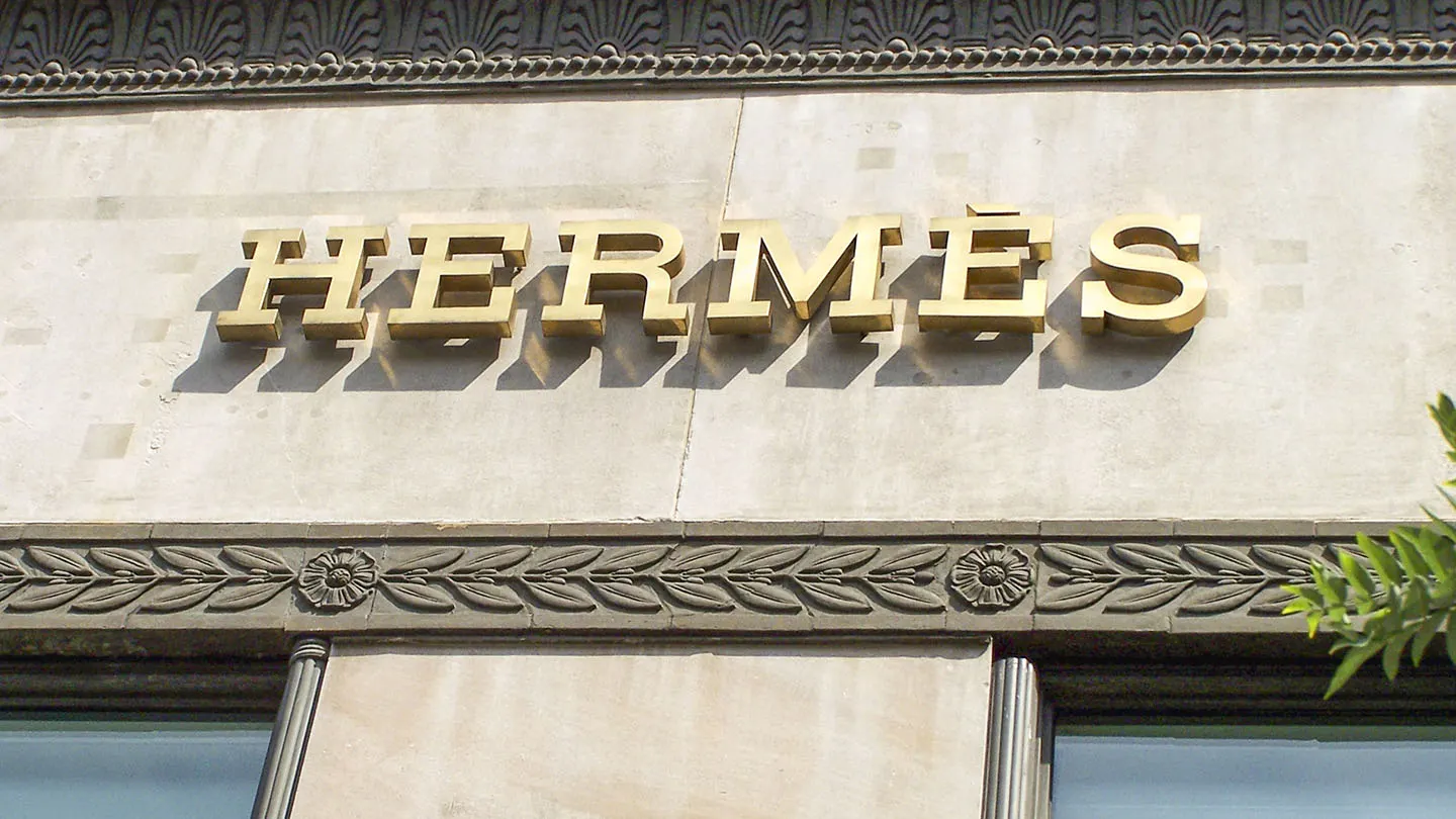 Gold HERMÈS letters mounted on a carved stone shopfront facade above two windows