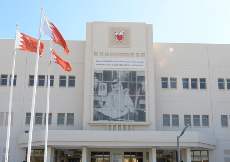 The headquarters of Bahrain's Information & eGovernment Authority, with its name in Arabic and English and the national emblem on the facade and Bahraini flags in front, Bahrain