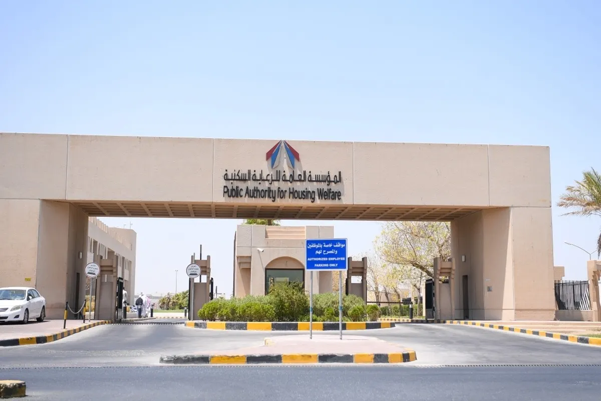 The entrance gate of the Public Authority for Housing Welfare in Kuwait, with the authority name in Arabic and English and its logo above the gateway