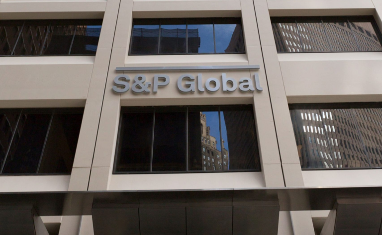 The S&P Global name in silver letters on the stone facade of an office building, with dark reflective windows above and below, United States.