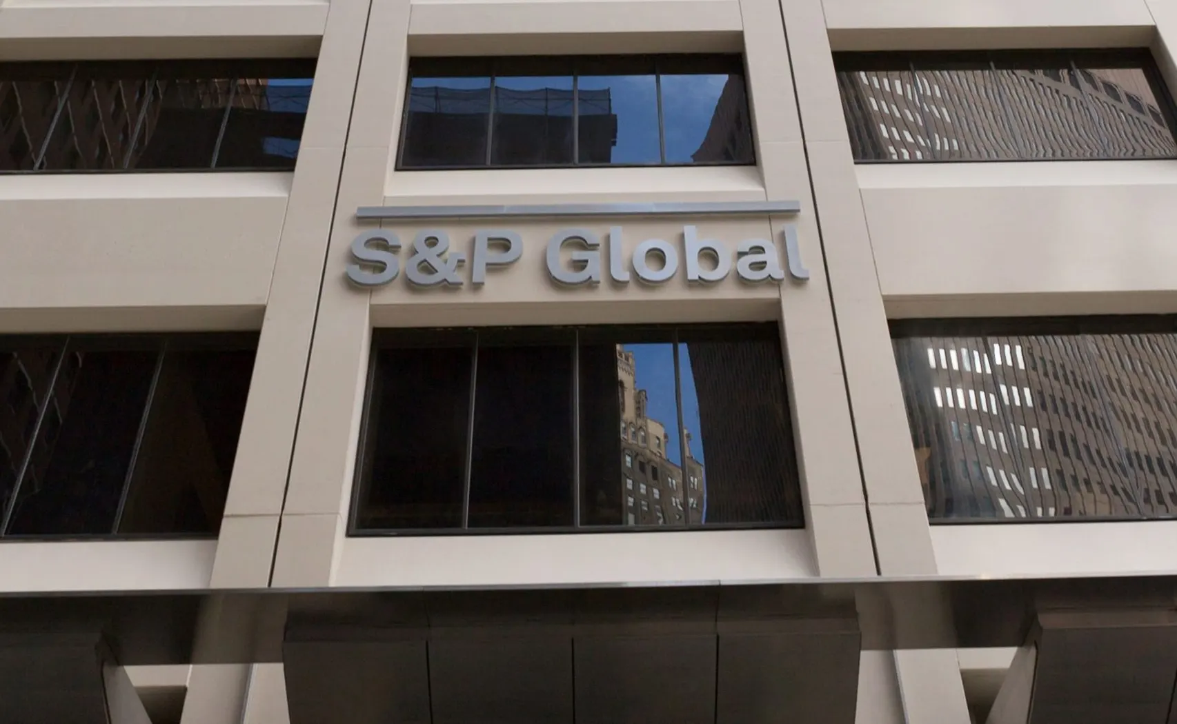 The S&P Global name in silver letters on the stone facade of an office building, with dark reflective windows above and below, United States.