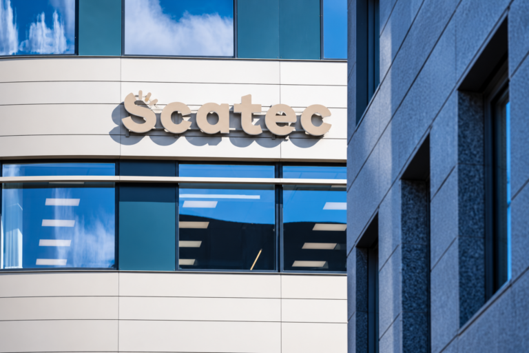 The Scatec logo on the curved facade of an office building with blue glass windows