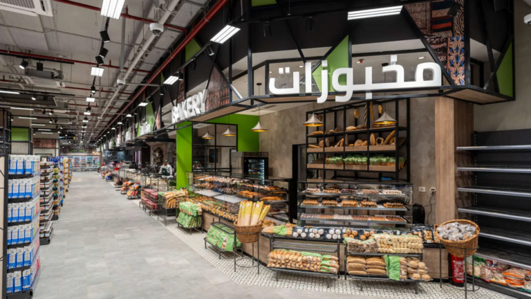 The bakery section of a modern supermarket in Egypt, with shelves of bread and pastries under a sign reading bakery in Arabic and English