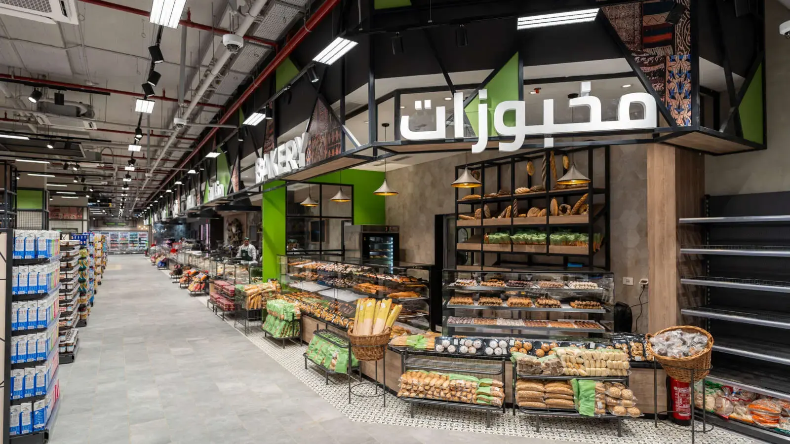 The bakery section of a modern supermarket in Egypt, with shelves of bread and pastries under a sign reading bakery in Arabic and English