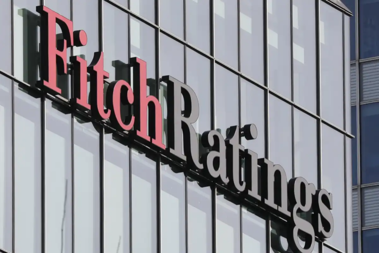 The Fitch Ratings name in red and grey letters on the glass facade of its offices at Canary Wharf in London