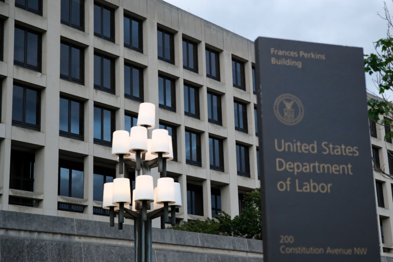 The United States Department of Labor sign outside the Frances Perkins Building at 200 Constitution Avenue NW, with the building's facade and a street lamp behind it