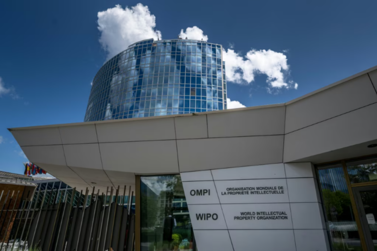 The entrance of the World Intellectual Property Organization headquarters in Geneva, with WIPO and OMPI signage beneath its curved blue glass tower