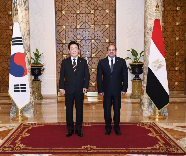 The presidents of Egypt and South Korea standing on a red carpet between the South Korean and Egyptian flags in an ornate hall, Cairo, Egypt
