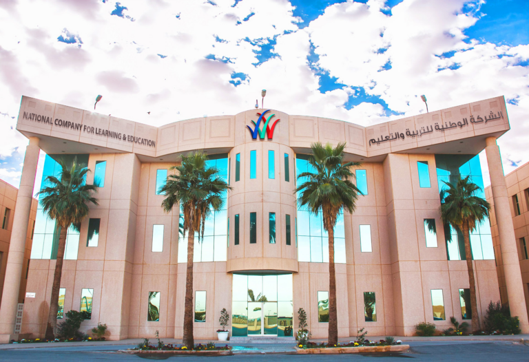 A school building with the National Company for Learning and Education name in English and Arabic on its facade and palm trees in front, Saudi Arabia