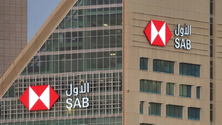 Saudi Awwal Bank's red and white hexagon logo with its Arabic and English names on the facade of a bank building