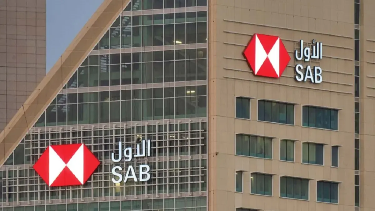 Saudi Awwal Bank's red and white hexagon logo with its Arabic and English names on the facade of a bank building