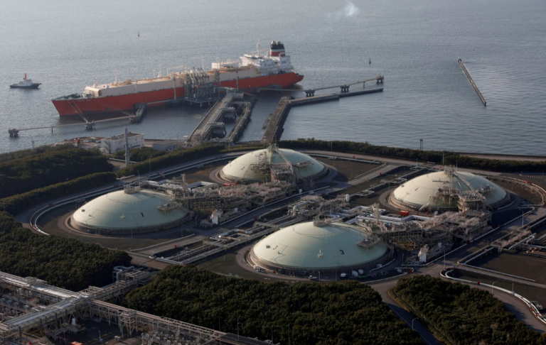 Aerial view of an LNG receiving terminal in Japan, with four domed storage tanks beside the sea and an LNG carrier moored at the jetty
